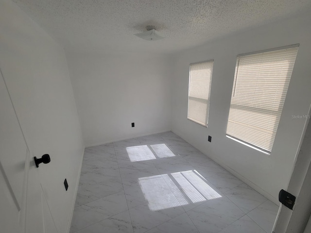 unfurnished room with a textured ceiling