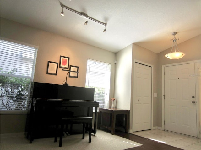 miscellaneous room with light tile patterned floors, rail lighting, and vaulted ceiling