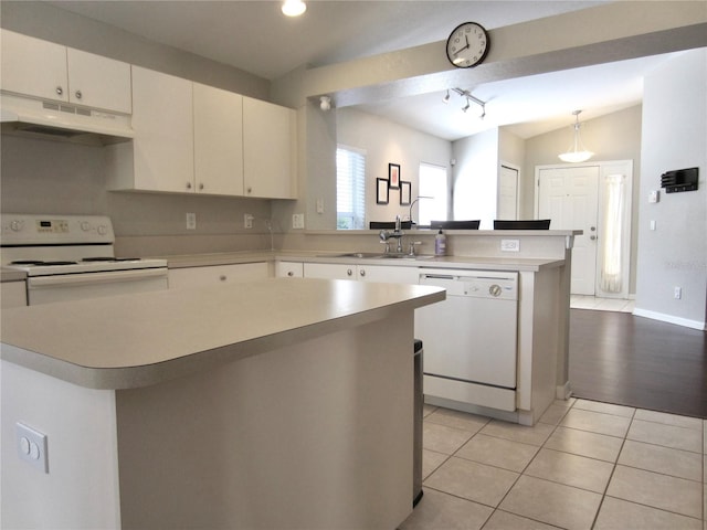 kitchen featuring sink, pendant lighting, vaulted ceiling, white appliances, and a kitchen island