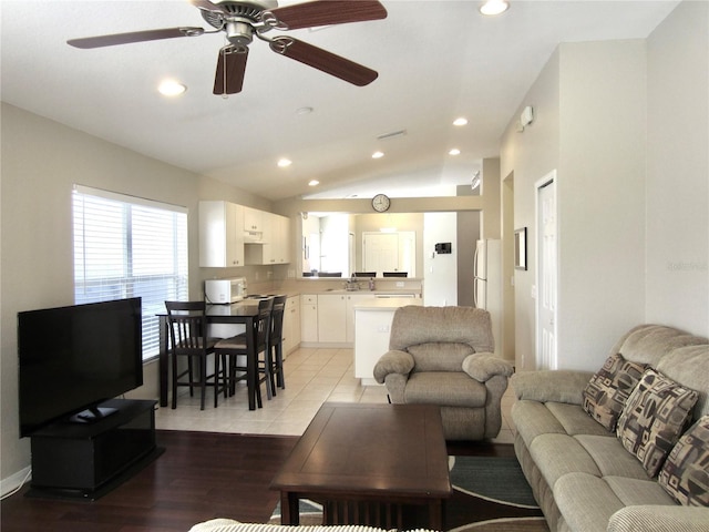 living room with ceiling fan, light hardwood / wood-style floors, sink, and vaulted ceiling