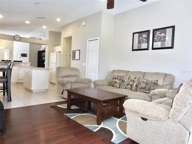 living room featuring ceiling fan, light hardwood / wood-style flooring, and vaulted ceiling