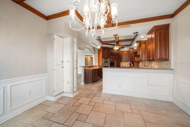 kitchen featuring stainless steel double oven, hanging light fixtures, ornamental molding, sink, and ceiling fan with notable chandelier