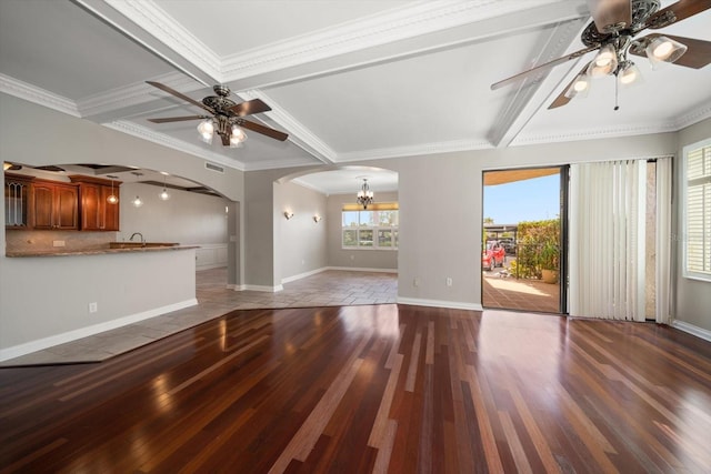 unfurnished living room with sink, ceiling fan with notable chandelier, beam ceiling, hardwood / wood-style flooring, and ornamental molding