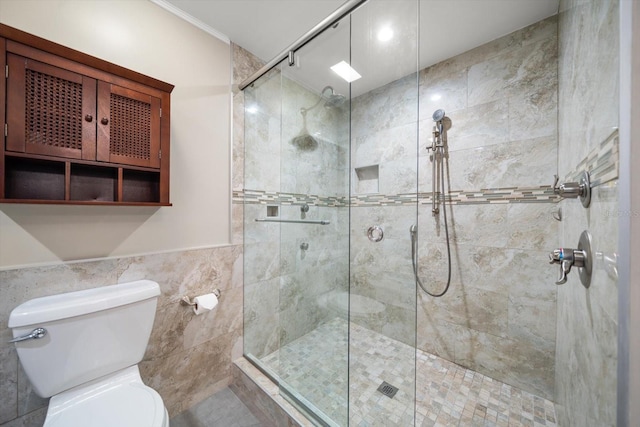 bathroom featuring toilet, a shower with shower door, and tile walls