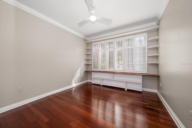 unfurnished room with crown molding, dark hardwood / wood-style floors, built in desk, and ceiling fan