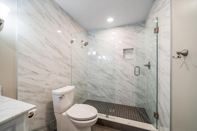 bathroom featuring a shower with door, vanity, toilet, and tile walls