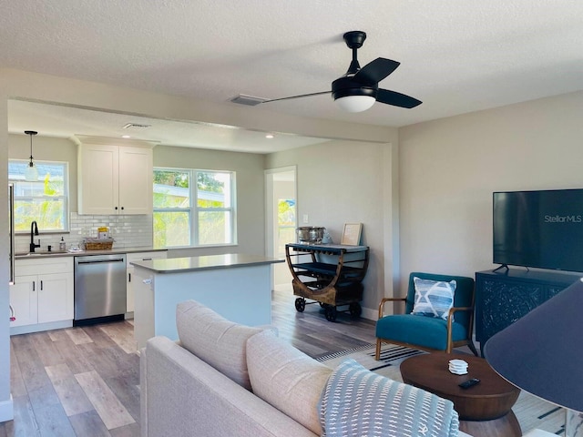 interior space featuring dishwasher, a center island, pendant lighting, white cabinets, and light hardwood / wood-style floors