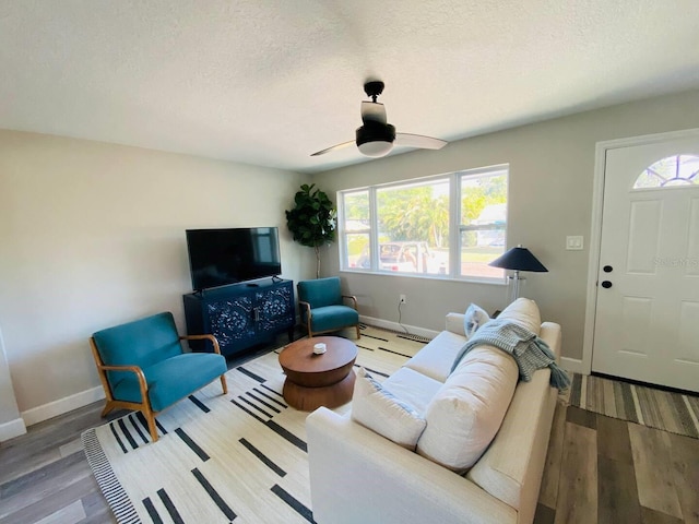 living room with ceiling fan, a textured ceiling, and light hardwood / wood-style flooring