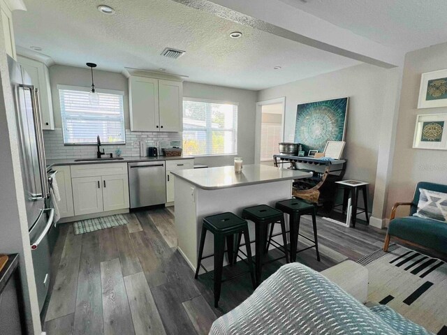 kitchen with dishwasher, sink, decorative light fixtures, white cabinets, and dark hardwood / wood-style flooring