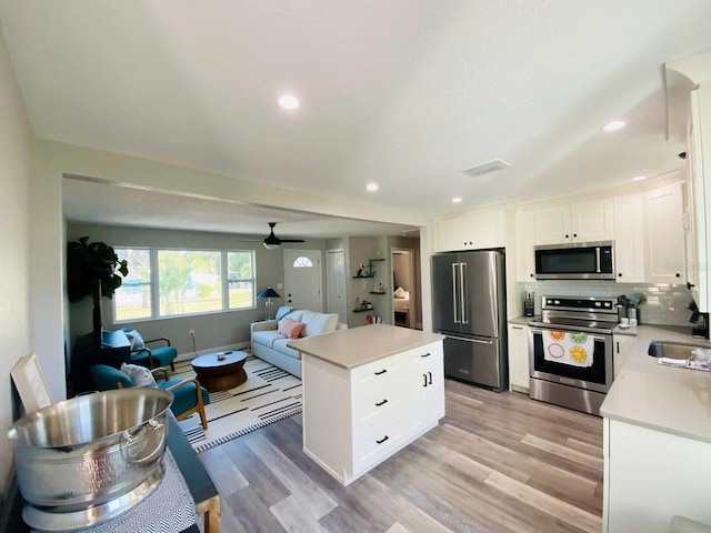 kitchen featuring light wood-type flooring, a center island, white cabinetry, ceiling fan, and stainless steel appliances