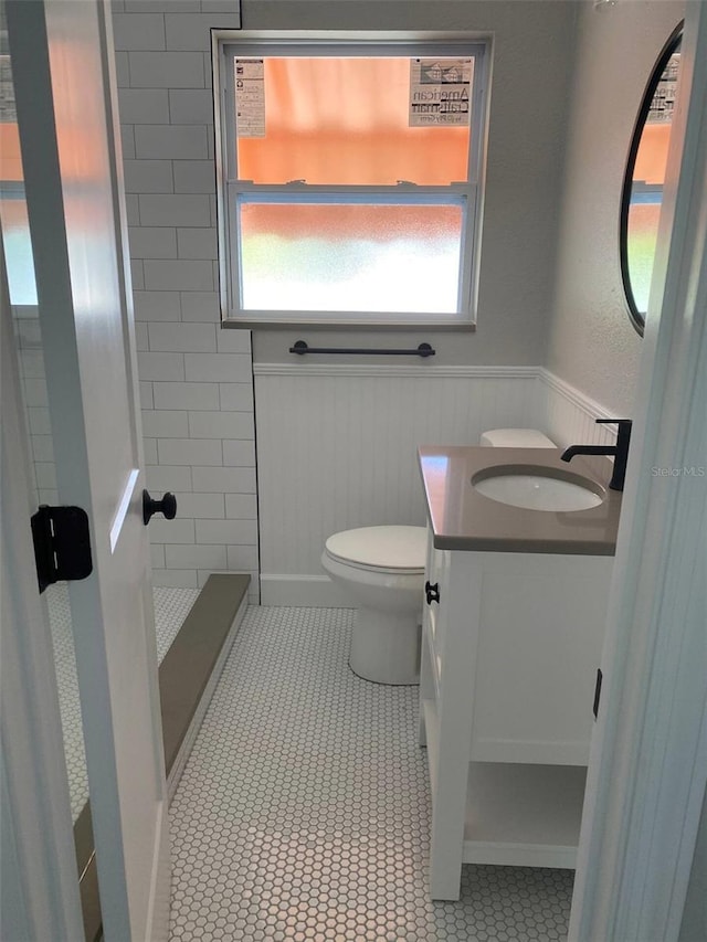 bathroom featuring vanity, tiled shower, toilet, and tile patterned flooring