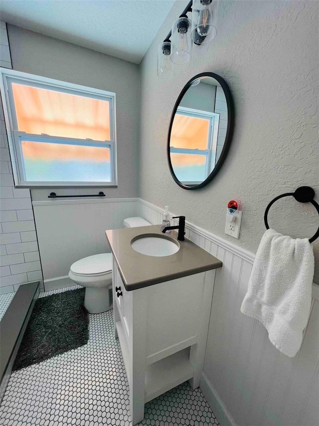 bathroom featuring vanity, toilet, tile patterned floors, and a textured ceiling