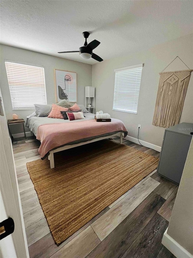 bedroom featuring ceiling fan, wood-type flooring, and a textured ceiling