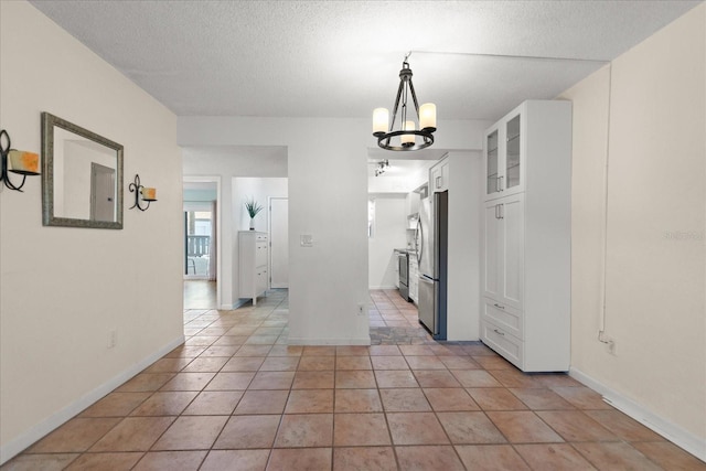 interior space with white cabinetry, a textured ceiling, electric panel, and stainless steel fridge