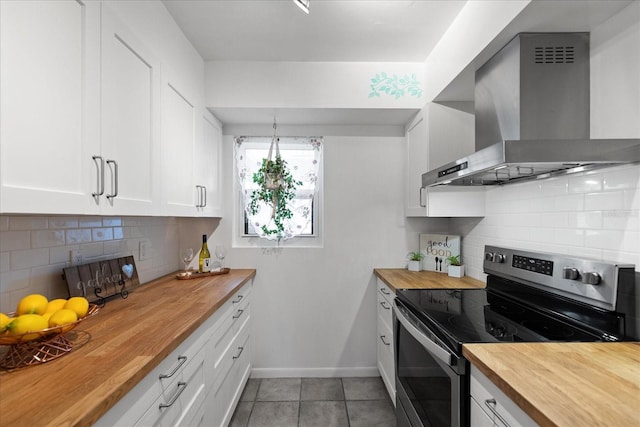 kitchen with stainless steel range with electric stovetop, wall chimney exhaust hood, white cabinetry, and wooden counters