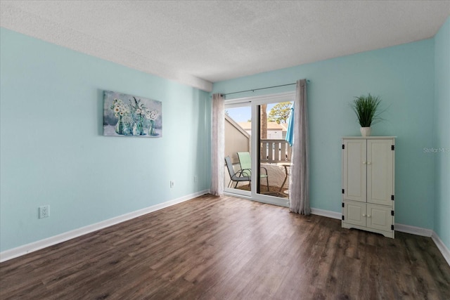 empty room featuring a textured ceiling and dark hardwood / wood-style floors