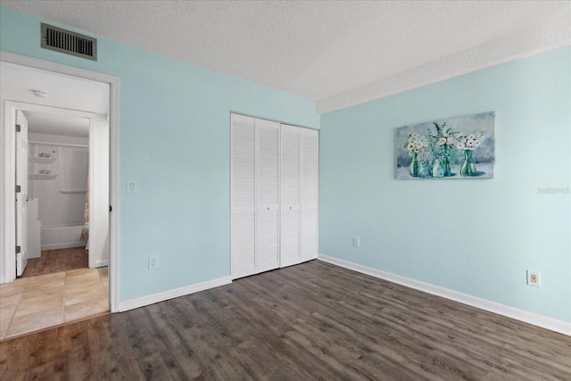 unfurnished bedroom featuring a closet, a textured ceiling, and wood-type flooring