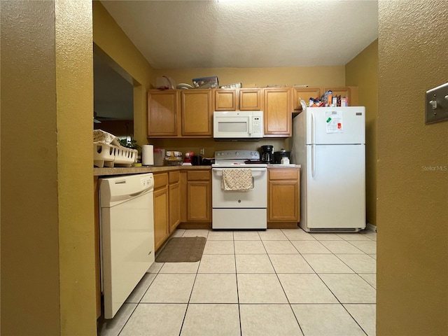 kitchen featuring a textured ceiling, light tile patterned flooring, and white appliances