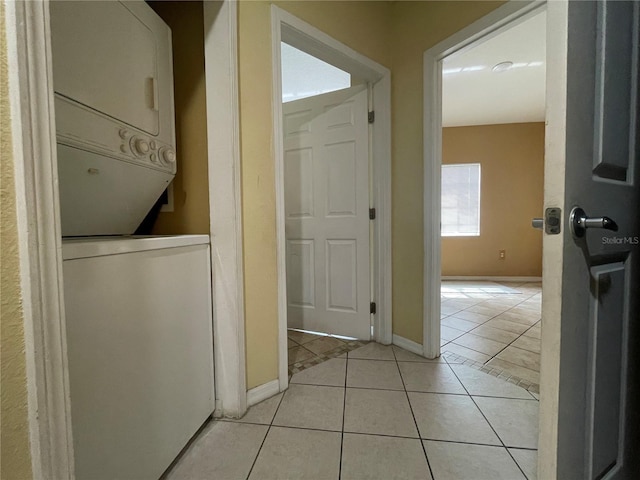 laundry room featuring stacked washer / dryer and light tile patterned flooring