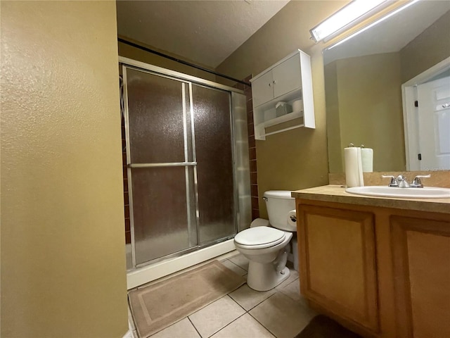 bathroom featuring toilet, a shower with shower door, vanity, and tile patterned floors