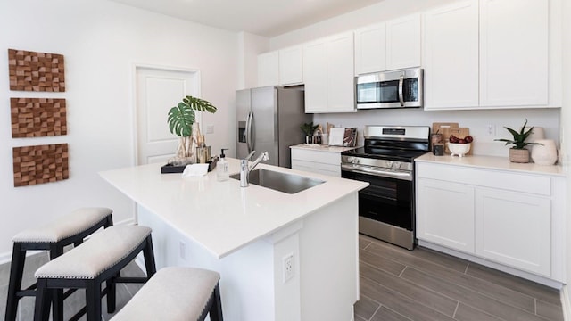 kitchen featuring white cabinetry, stainless steel appliances, sink, and an island with sink