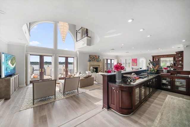 kitchen with a peninsula, a fireplace, open floor plan, french doors, and light wood-type flooring