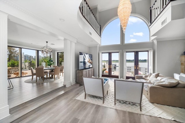 living room with a chandelier, french doors, crown molding, and a healthy amount of sunlight