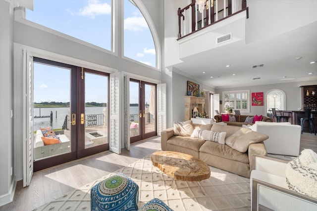 living area featuring a wealth of natural light, french doors, a water view, and visible vents