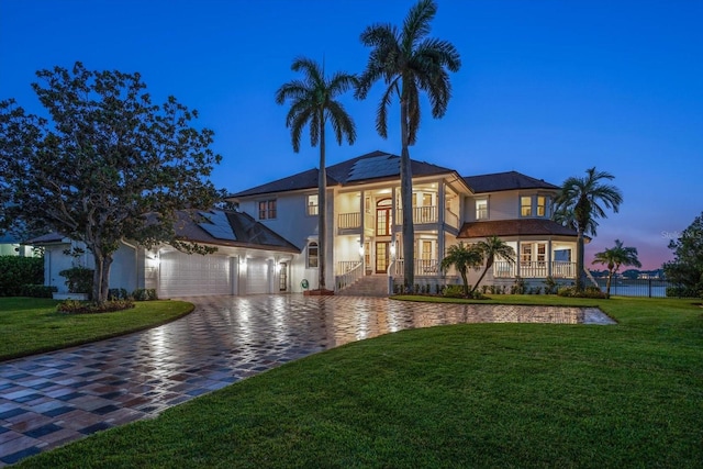 view of front facade featuring solar panels, a yard, decorative driveway, and a balcony