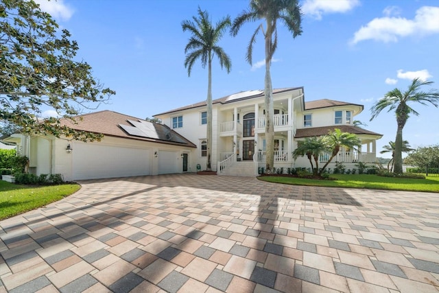 view of front of property with an attached garage, a balcony, decorative driveway, and solar panels