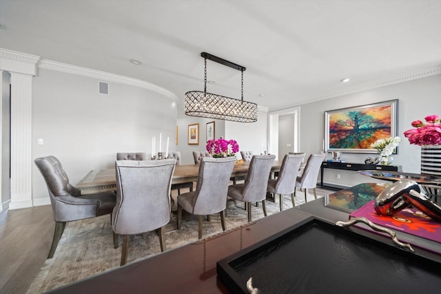 dining area featuring crown molding, ornate columns, visible vents, wood finished floors, and baseboards