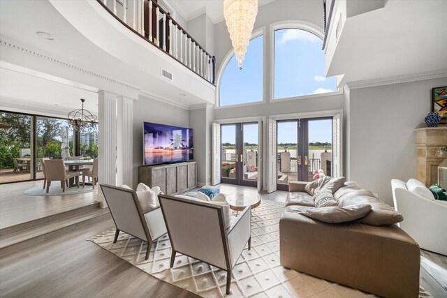 living area featuring light wood finished floors, visible vents, ornamental molding, french doors, and a notable chandelier