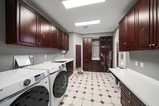 laundry room with a sink, cabinet space, light floors, washing machine and clothes dryer, and crown molding