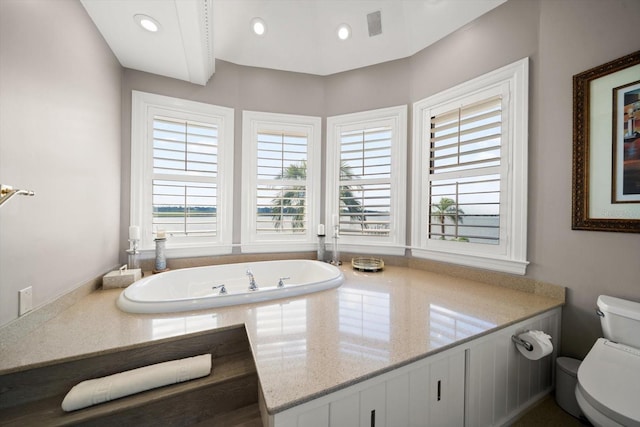 full bath with toilet, visible vents, a relaxing tiled tub, and recessed lighting