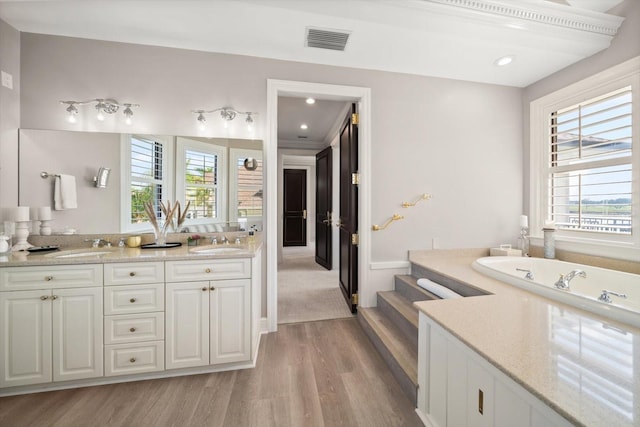 full bathroom with double vanity, plenty of natural light, visible vents, and wood finished floors