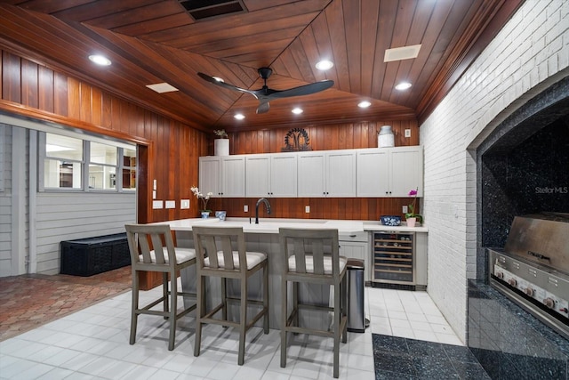 kitchen featuring visible vents, wooden ceiling, wine cooler, light countertops, and white cabinetry