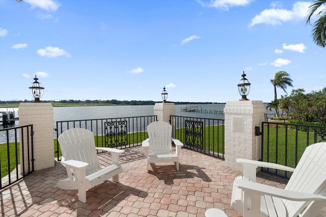 view of patio with a gate and a water view