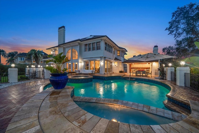 view of swimming pool with a pool with connected hot tub, fence, and a patio