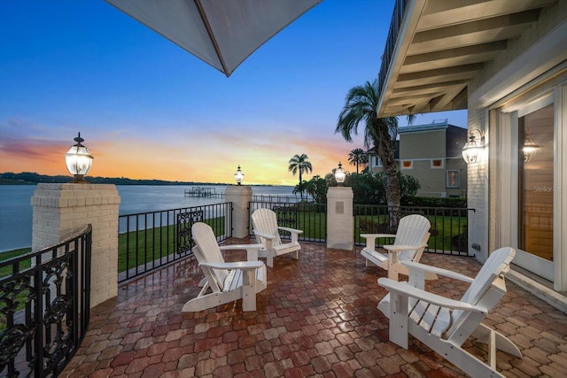 patio terrace at dusk featuring a water view