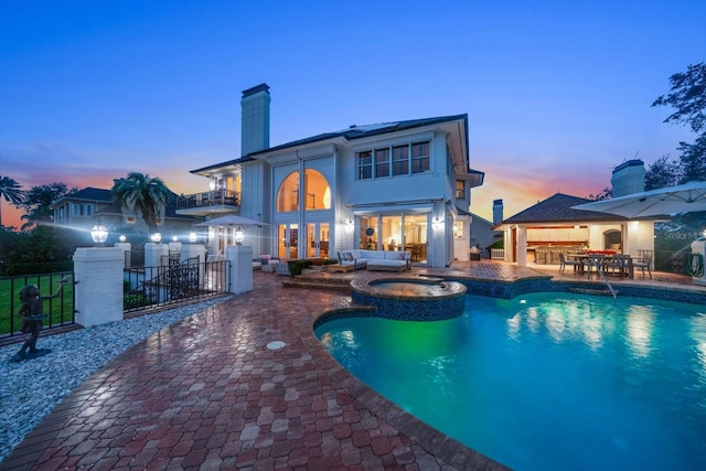 view of pool featuring a patio area, a pool with connected hot tub, fence, and outdoor lounge area