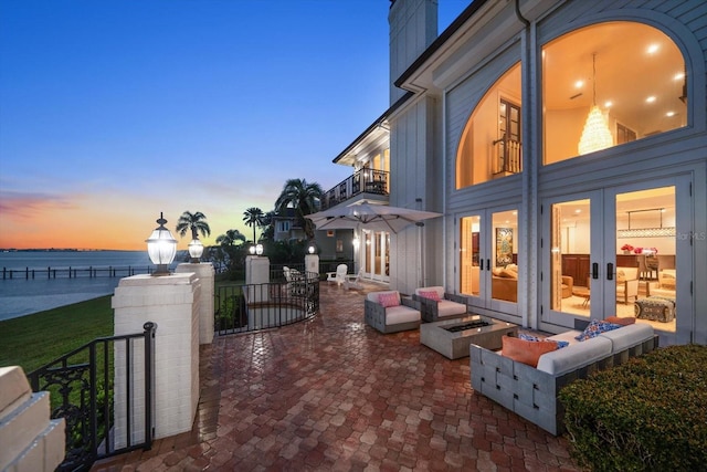 exterior space with french doors, an outdoor fire pit, and a water view