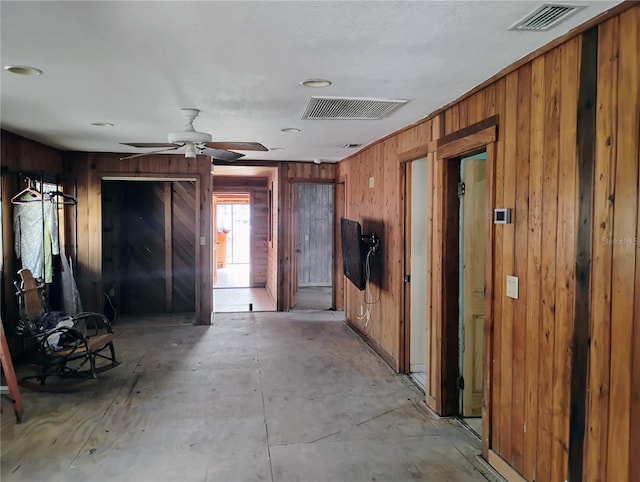 misc room with ceiling fan and wooden walls