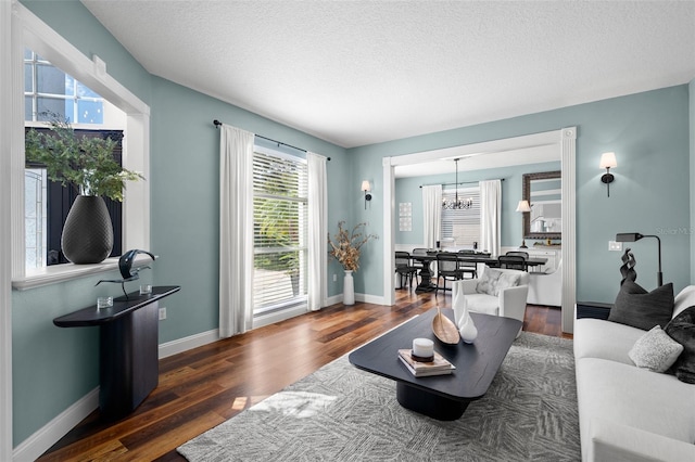 living room with dark hardwood / wood-style floors, an inviting chandelier, and a textured ceiling