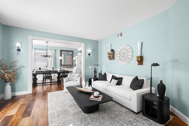 living room featuring hardwood / wood-style flooring, a textured ceiling, and a chandelier