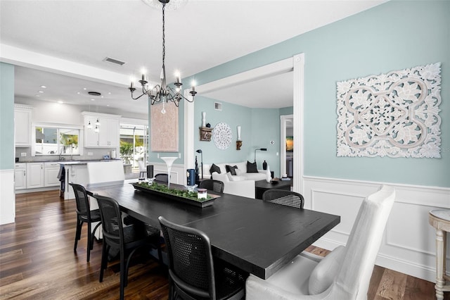 dining area with a notable chandelier, sink, and dark hardwood / wood-style floors