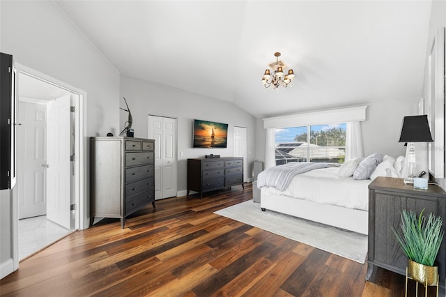 bedroom featuring dark wood-type flooring, lofted ceiling, and a notable chandelier