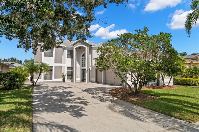 view of front of home with a garage, stucco siding, driveway, and a front lawn