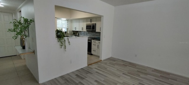 kitchen featuring tasteful backsplash, white cabinetry, light hardwood / wood-style flooring, and stainless steel appliances