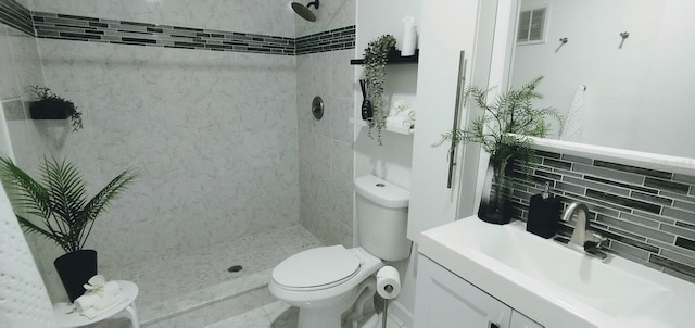 bathroom featuring vanity, toilet, a tile shower, and backsplash