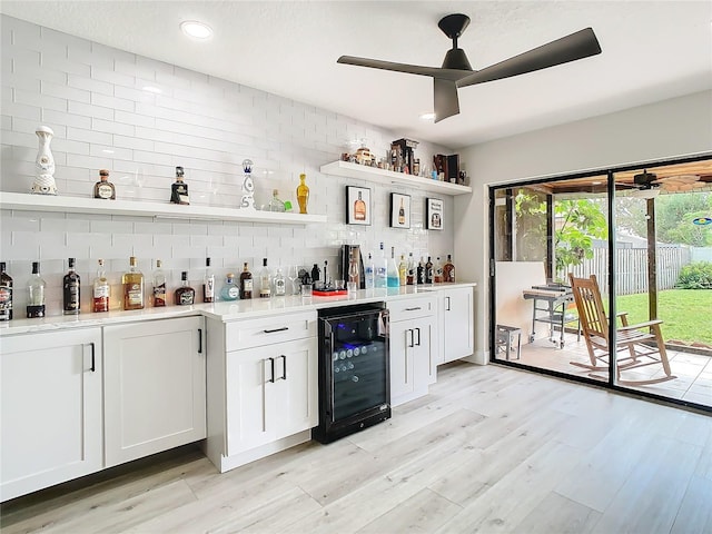 bar with white cabinetry, ceiling fan, light hardwood / wood-style floors, and beverage cooler